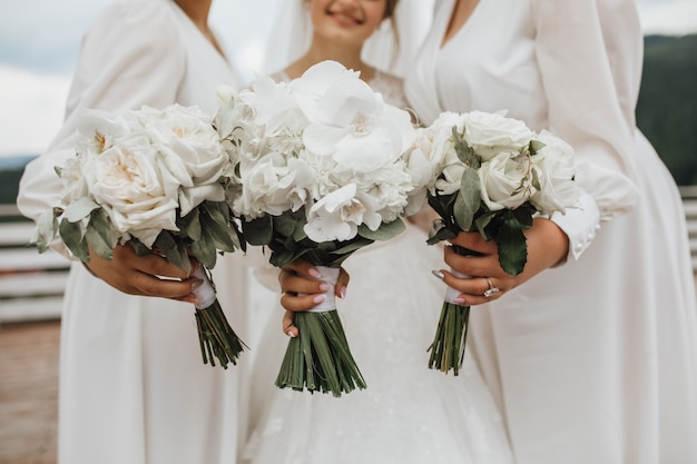 Free photo white wedding bouquets for bride and bridesmaids made of callas and orchids in hands outdoors