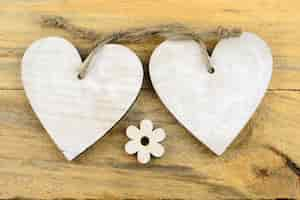 Free photo white wooden hearts and a flower on a wooden surface