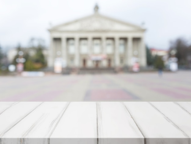 Free photo white wooden table in front of blurred classical public building fa�ade