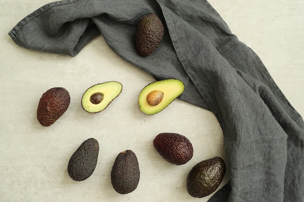 Free photo whole and cut avocados on gray cloth