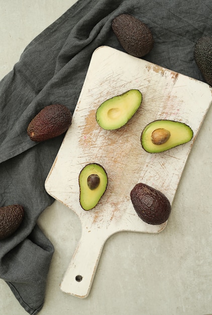 Free photo whole and cut avocados on wooden cutting board