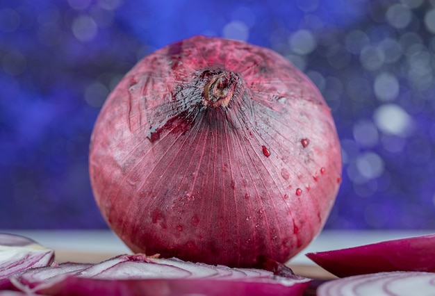 A whole onion with slices on a colorful wall.