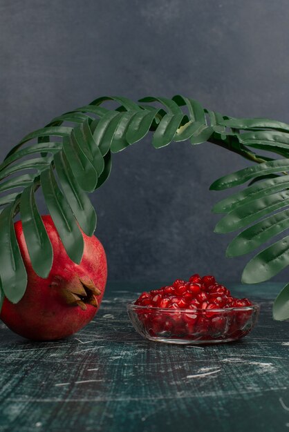 Free photo whole pomegranate and seeds on marble table