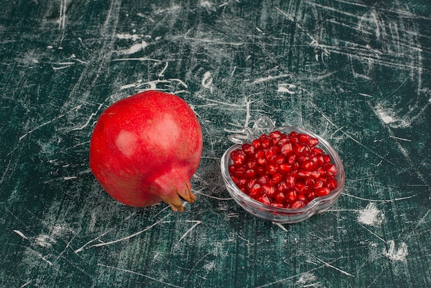 Whole pomegranate and seeds on marble table.