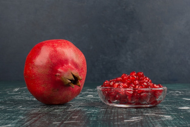 Free photo whole pomegranate and seeds on marble table.