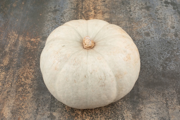 Whole single grey pumpkin on marble wall.