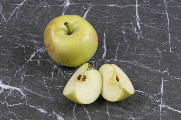 Whole and sliced apples on marble.