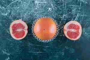 Free photo whole and sliced grapefruits on marble table.