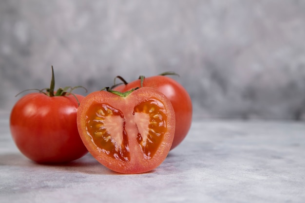 Whole and sliced juicy red tomatoes placed on marble