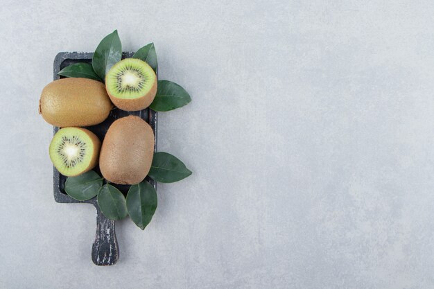 Whole and sliced kiwis on black cutting board