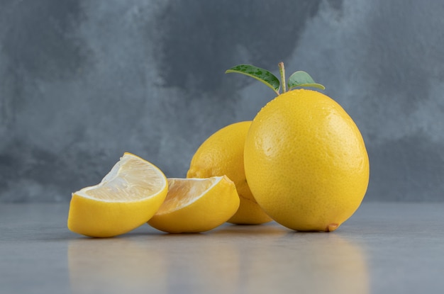 Whole and sliced lemons displayed on marble 