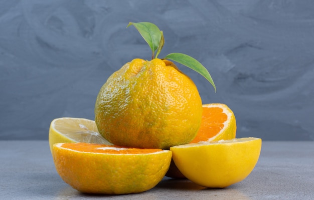 Whole tangerine on lemon and tangerine slices on marble background. 