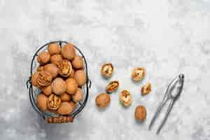 Free photo whole walnuts in shell in food metal basket, walnut kernels. top view on concrete