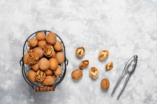 Free Photo whole walnuts in shell in food metal basket, walnut kernels. top view on concrete 