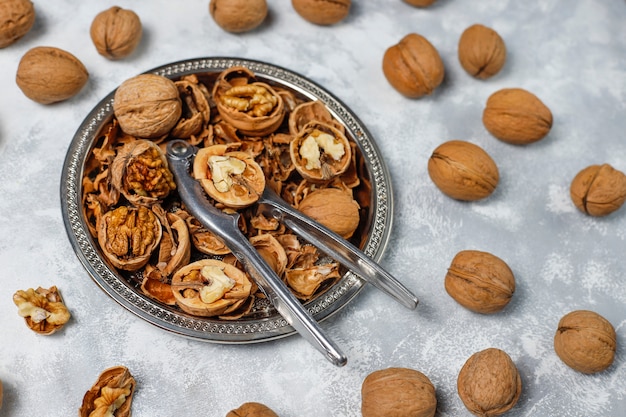 Free photo whole walnuts in shell in food metal basket, walnut kernels. top view on concrete