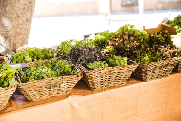 Free photo wicker basket of fresh leafy vegetables arranged in row at market stall