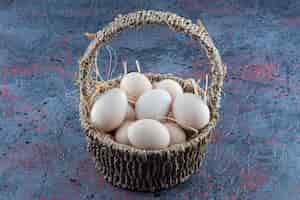 Free photo a wicker basket full of fresh raw chicken eggs