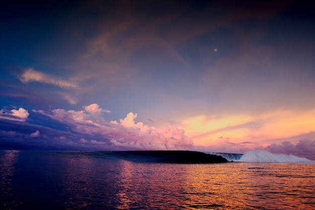 Wide angle shot of a mesmerizing sunset in the ocean under a sky full of multicolored clouds