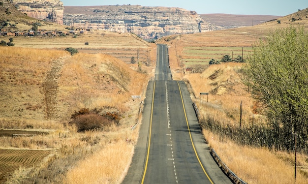 Free photo wide angle shot of a road going on a mountain surrounded by bushes and dry grass