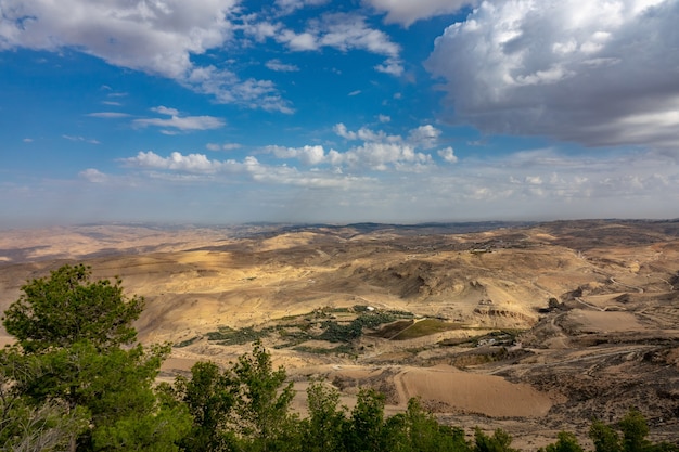 Wide angle shot of a valley of trees and mountains under a sky full of clouds