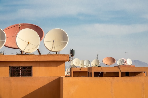 Free Photo wide angle shot of white satellite dishes on the roof of a building