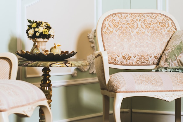 Free photo wide closeup shot of a flower bouquet in a vase on a table near an elegant armchair