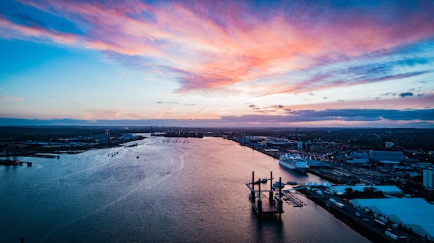 Free photo wide distant shot of boats floating on the body of water in the city under a pinkish sky