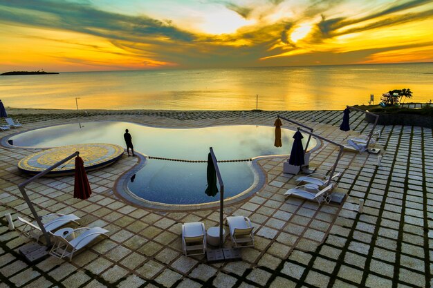 Free photo wide high angle shot of a private pool with an ocean in the background during sunset hour