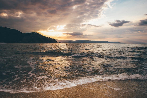 Free Photo wide landscape shot of a sea near mountains in the distance under a sky during sunset