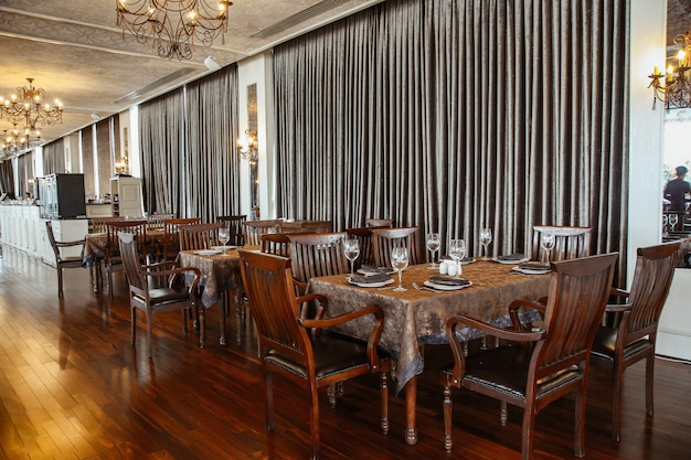 Wide restaurant hall with wooden table and chairs for 6 persons