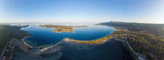 Free photo wide shot of the aegean sea coast with a town on the shore and island, blue transparent water, greenery around, pamorama view from the drone, greece