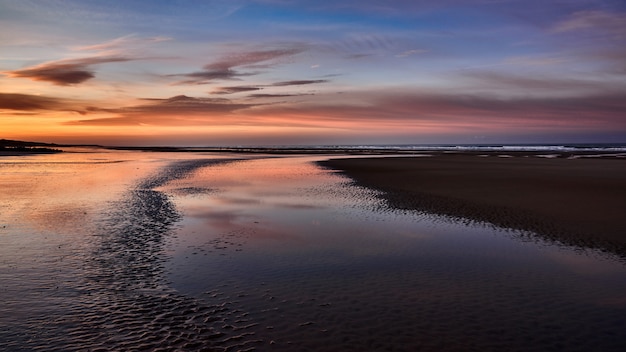 Free photo wide shot of the beautiful coast of the sea with the amazing cloudy sky during golden hour