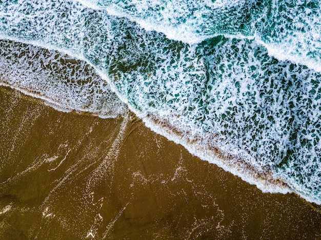 Free photo wide shot of blue sea waves on a sandy seashore