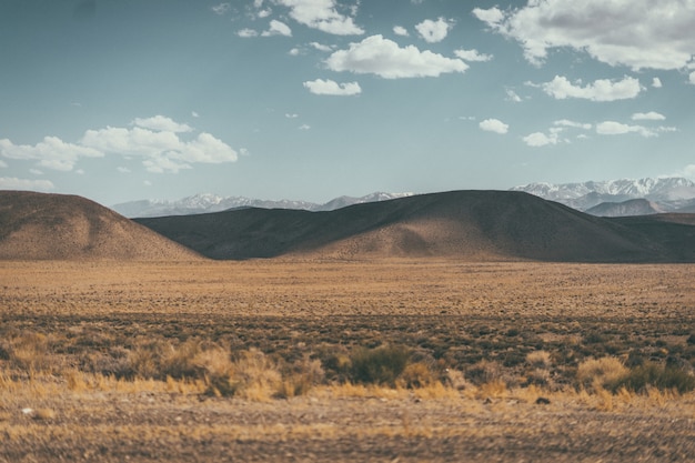 Wide shot of a desert valley with hills and mountains