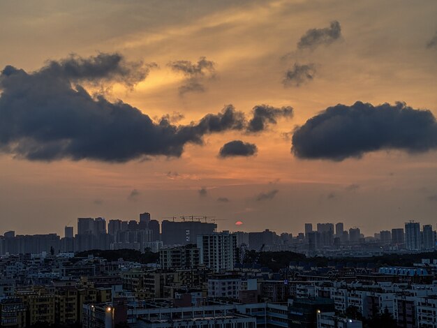 Wide shot of a modern and busy city with dark clouds and orange sky