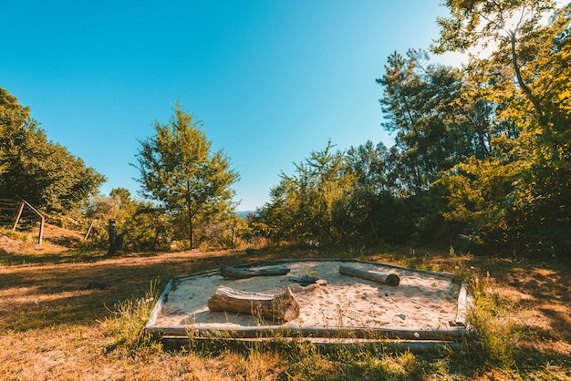 Free Photo wide shot of a park with a firepit in a sandbox surrounded by plants and trees