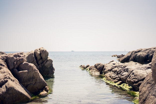 Wide shot of rock formations on the body of water under a clear sky