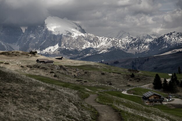 Wide shot of a small cabins near mountains covered with snow under a cloudy sky