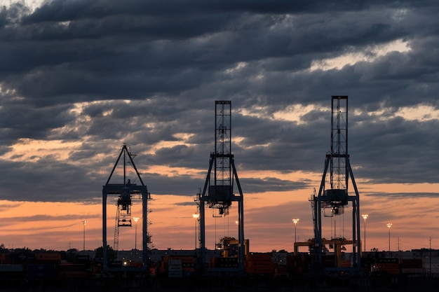 Free photo wide shot of three towers in a port during sunset on a cloudy day