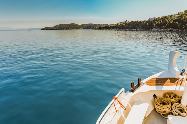 Free Photo wide shot of a white canoe on the body of water near a green island under a clear blue sky