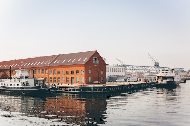 Free photo wide shot of white yachts on the body of water near a port with orange houses