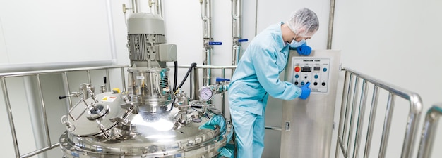 Free photo widescreen picture scientist in blue lab suit check control panel near big chromed tanks