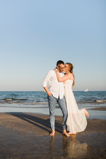 Wife kissing her husband near the seashore at beach