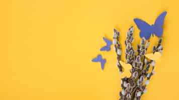 Free photo willow branches with paper butterflies on yellow table