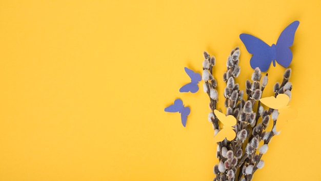 Free Photo willow branches with paper butterflies on yellow table