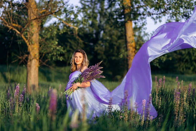 Free Photo wind blows pregnant woman's violet dress while she stands in the field of lavender