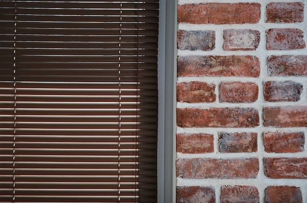 Free photo window with brown blinds and a brick wall made of old bricks loft interior industrial interior as a background closeup