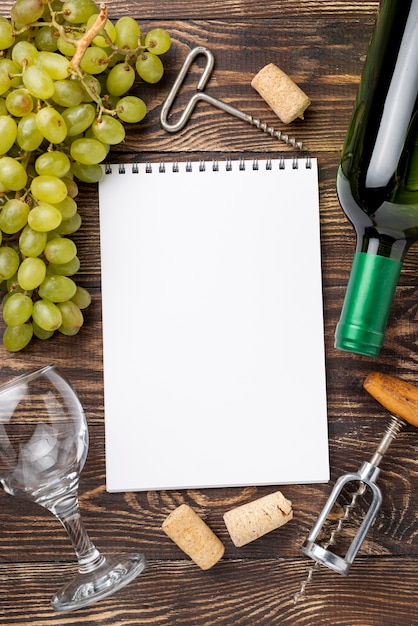 Wine bottle and grapes beside notebook