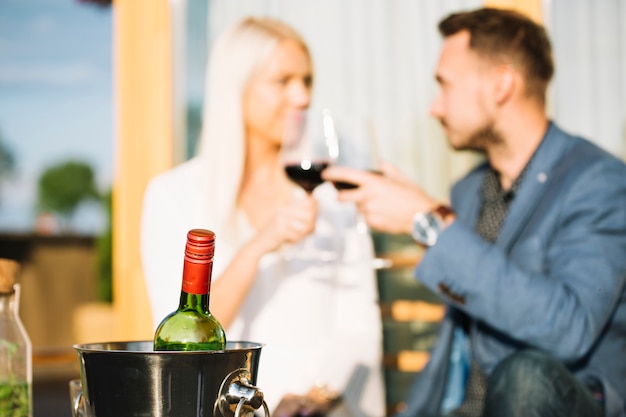 Free photo wine bottle in ice bucket with couple toasting wine glasses