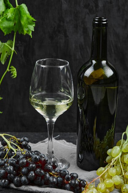 A wine glass with a bunch of red grapes on the table. 